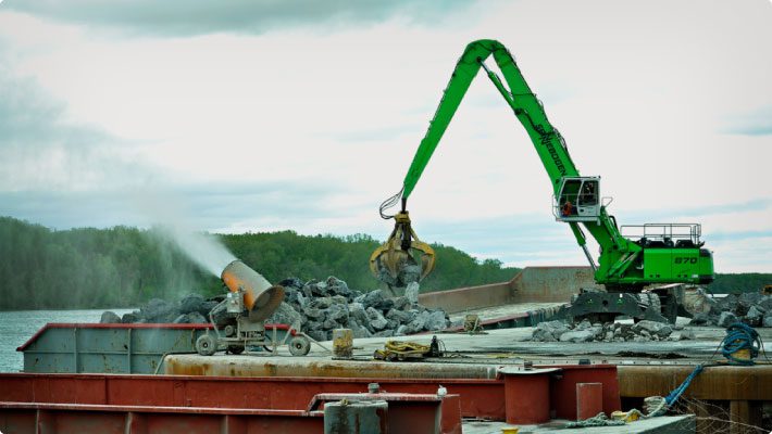 Crane loading bulk cargo with dust control system for suppression at port terminal