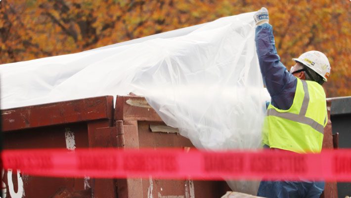 Worker avoid effects of fugitive dust at waste container