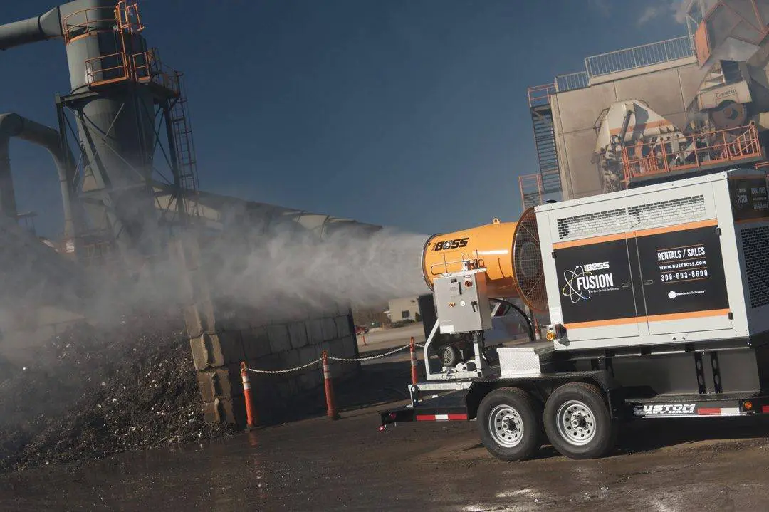A truck sprays water on a dirt pile to control dust at a scrap metal recycling site in the USA.
