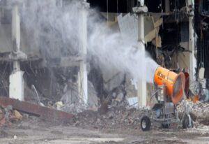 A dust suppression cannon sprays water on a destroyed building in the USA.