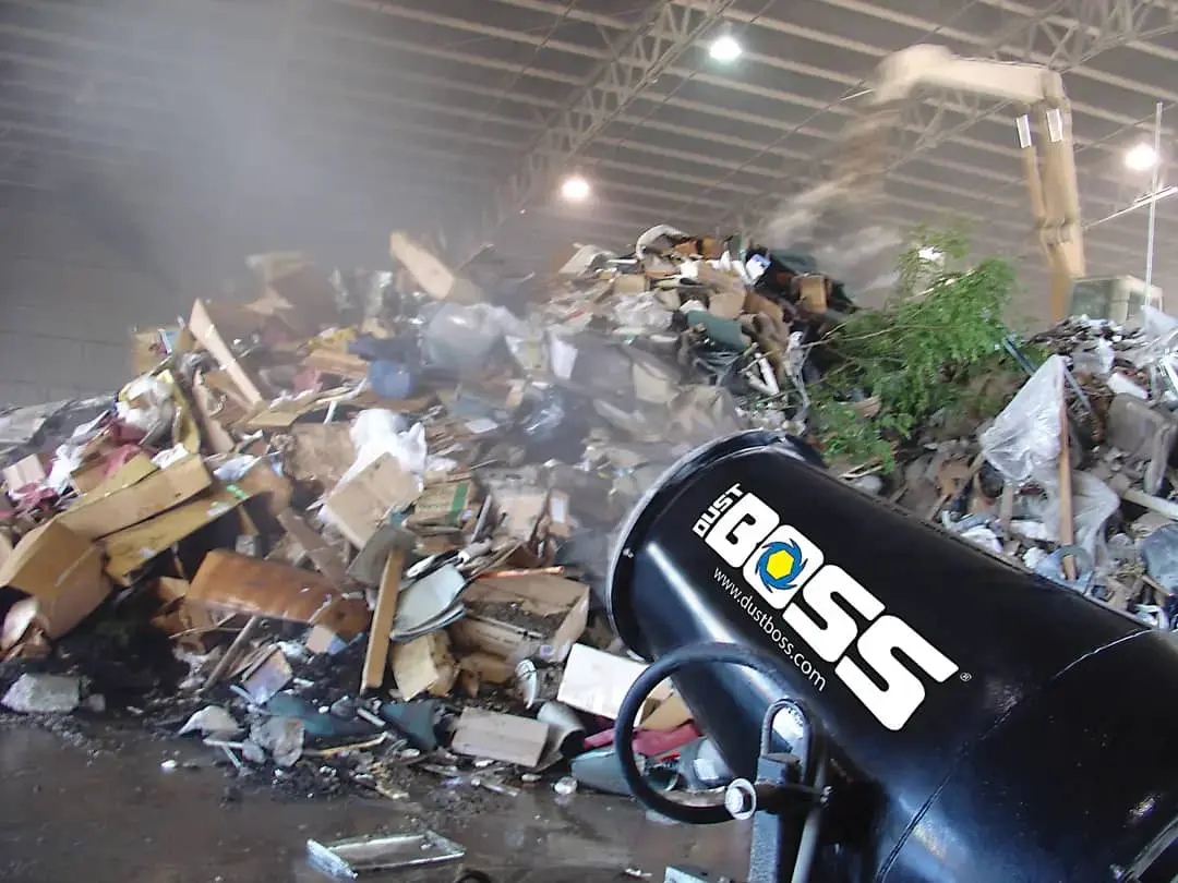 A large pile of trash beside a heavy machine used for waste management and disposal