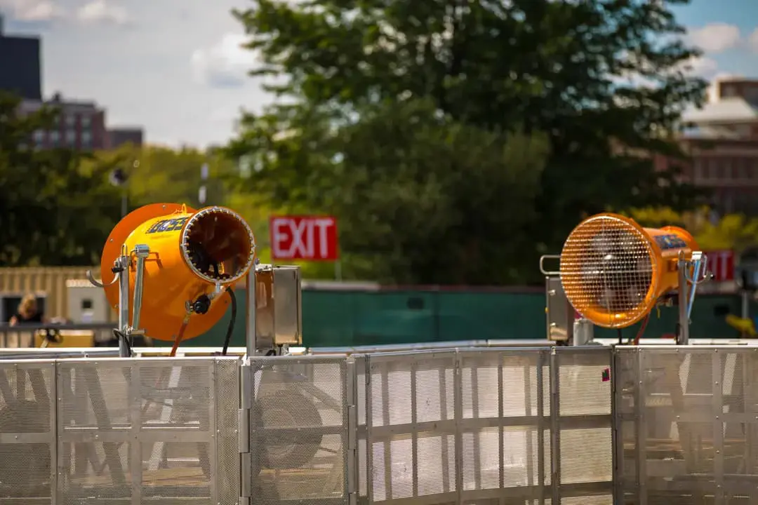 Two orange dustboss mounted on a metal fence, ready for emergency use in a public area