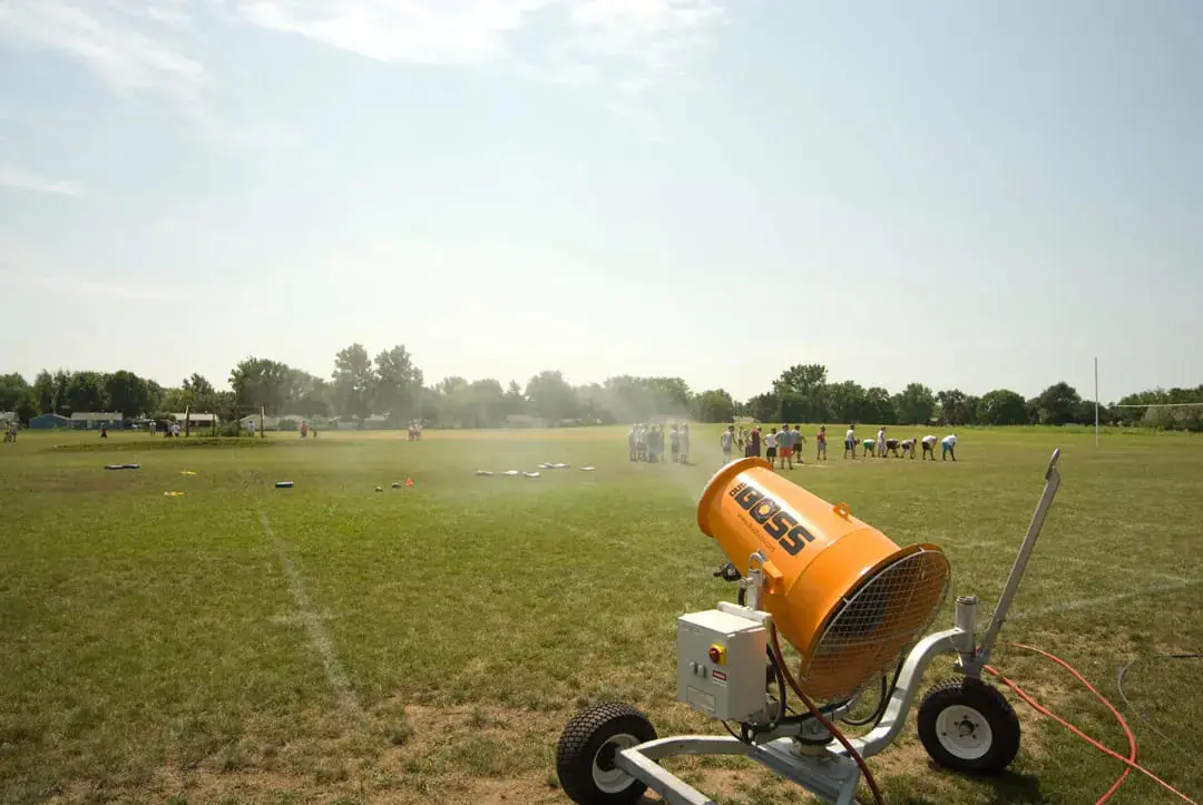 A portable air compressor is positioned on a soccer field beside a soccer ball, prepared for inflation tasks
