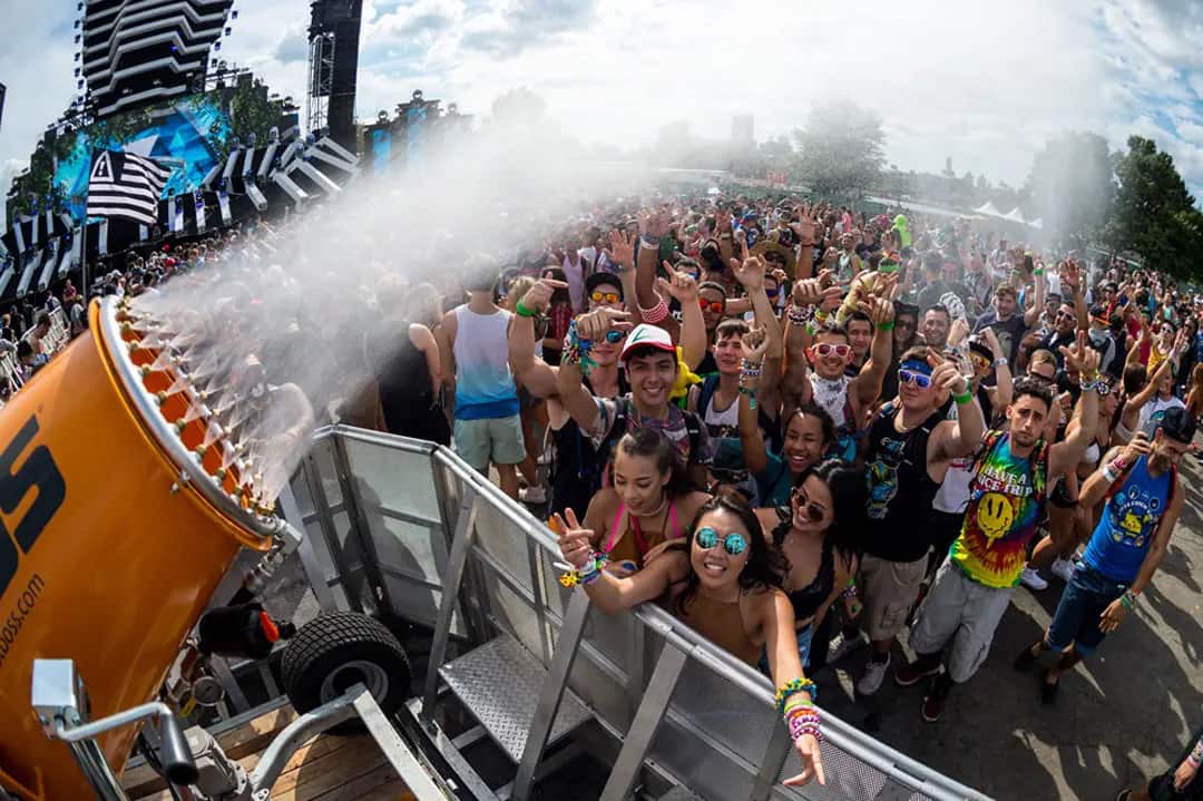 Festival-goers cheer as water sprays from a cannon, creating a refreshing atmosphere at a lively outdoor music event