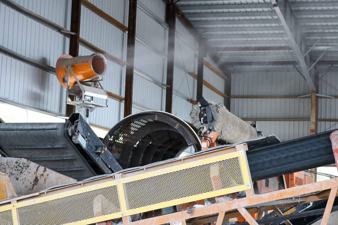 A man operates a conveyor belt in a warehouse, focused on his task amidst boxes and equipment