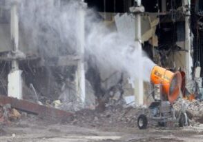 A dust suppression cannon sprays water on a destroyed building in the USA.